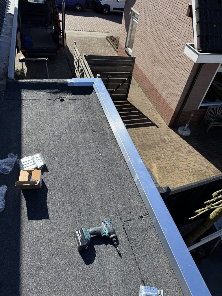 Nieuw bitumen plat dak met daktrim naast pannendak van woning in Apeldoorn