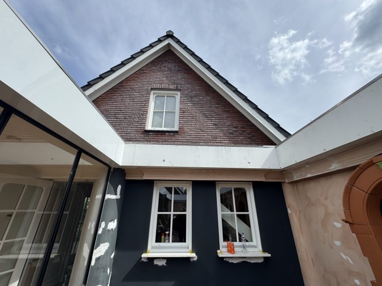 Witte boeidelen en dakranden vernieuwd rondom een binnenplaats met buitenhaard in Apeldoorn