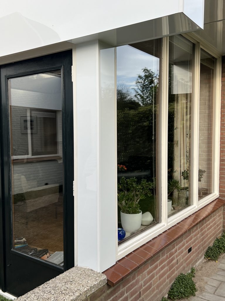 Dakrand en boeidelen met nieuwe witte beplating op woning met plat dak in Apeldoorn