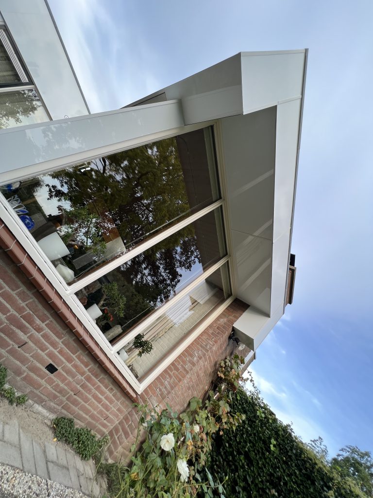 Dakrand en boeidelen met nieuwe witte beplating op woning met plat dak in Apeldoorn
