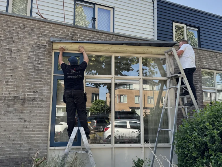 Dakdekkers plaatsen nieuw hout boven de raampartij na het verwijderen van het verrotte boeideel in Beekbergen