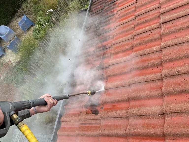 Dakdekker reinigt vervuilde rode dakpannen in Warnsveld met een hogedrukreiniger